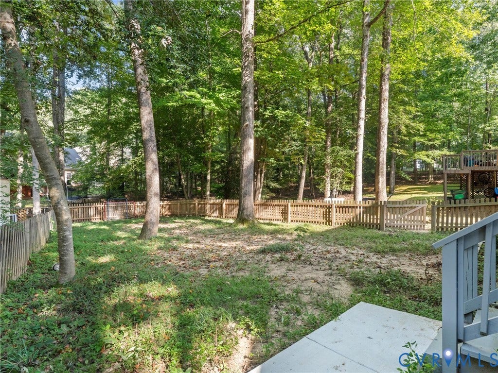 Expansive backyard featuring mature trees and wood fencing