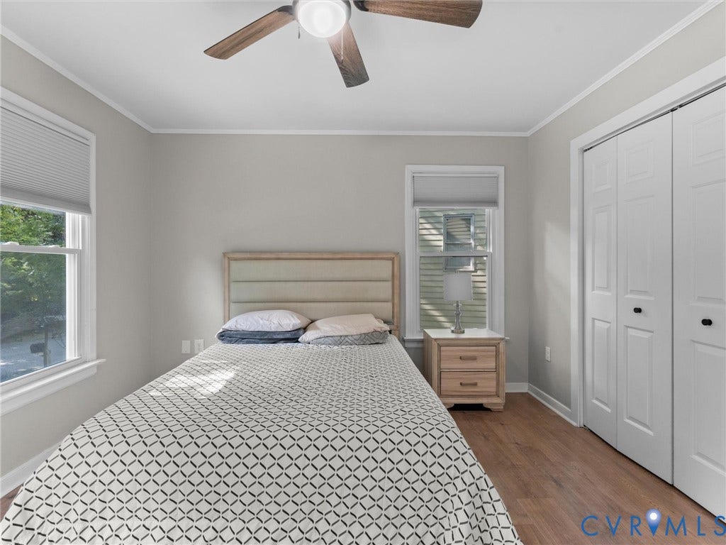 Wood-finish flooring with white trim, ceiling fan with wood-finish blades, and white bi-fold closet doors