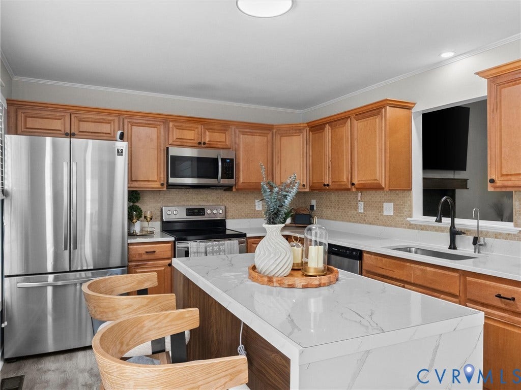 Kitchen featuring wood cabinetry, stainless steel appliances, white countertop, and tile backsplash