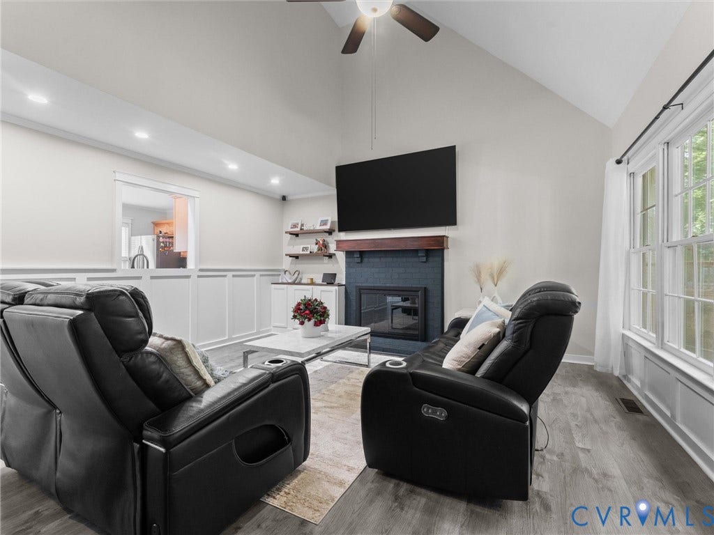 Vaulted ceiling, wood-finish flooring, recessed lighting, fireplace with dark tile surround, and built-in shelving