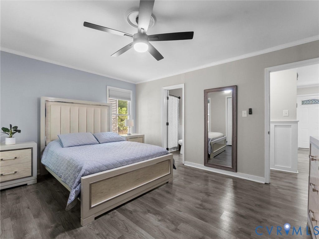 Wood-finish flooring throughout, featuring a ceiling fan with integrated lighting, crown molding, and a window with blinds