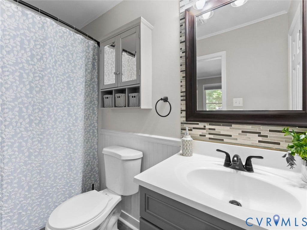 Vanity with an integrated sink and black faucet, wood-framed mirror, and a mosaic tile backsplash