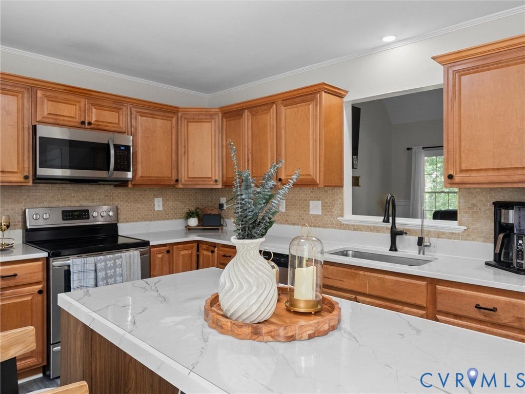 Kitchen featuring wood cabinetry, stainless steel appliances, white countertops, and a tile backsplash