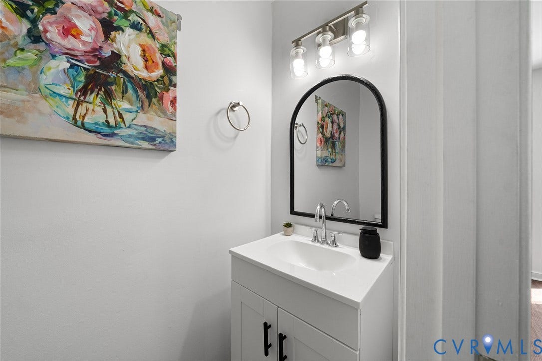 8414 Whirlaway Drive, Matoaca, Midlothian, VA 23112 Integrated vanity with a white countertop and basin, arched mirror with a black frame, and brushed nickel light fixture