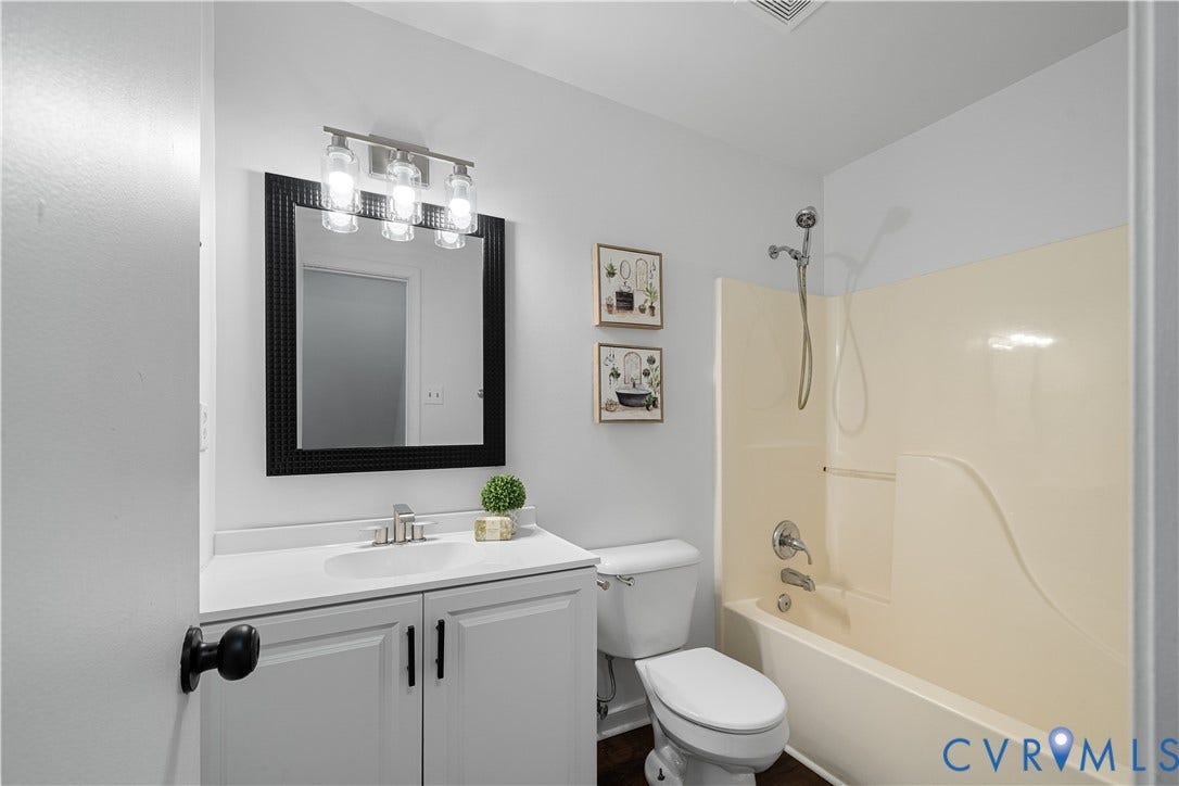 8414 Whirlaway Drive, Matoaca, Midlothian, VA 23112 Vanity with white cabinetry and integrated sink, framed mirror, three-light fixture, and a combination tub/shower