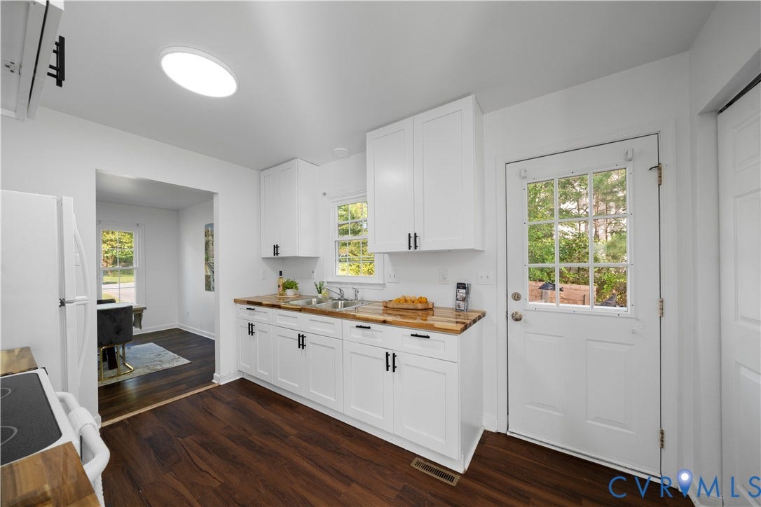 8414 Whirlaway Drive, Matoaca, Midlothian, VA 23112 White cabinetry with matte black hardware, wood-finish countertops, stainless steel sink with a goose-neck faucet, dark wood-finish flooring, and a glass-paned door