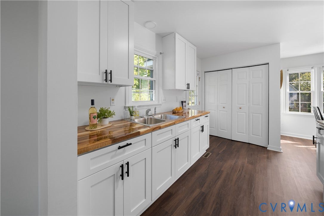 8414 Whirlaway Drive, Matoaca, Midlothian, VA 23112 White shaker-style cabinetry with matte black hardware, wood-finish countertops, stainless steel double-basin sink, and dark wood-finish flooring