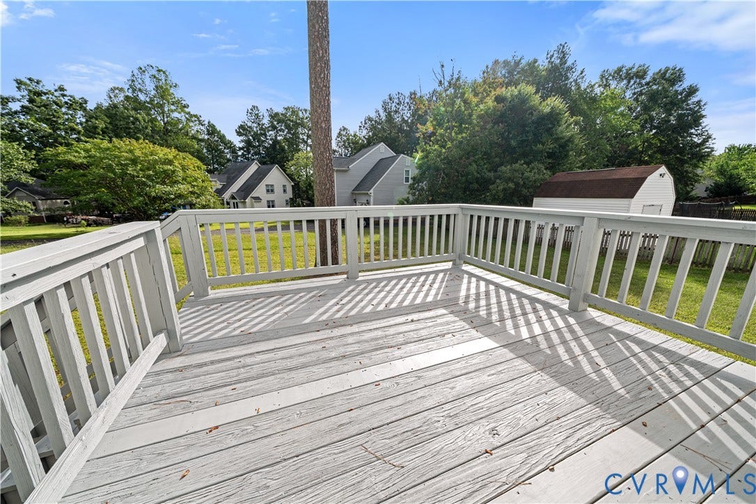 8414 Whirlaway Drive, Matoaca, Midlothian, VA 23112 Expansive outdoor deck with painted railings, overlooking a large grassy yard with mature trees and a detached shed