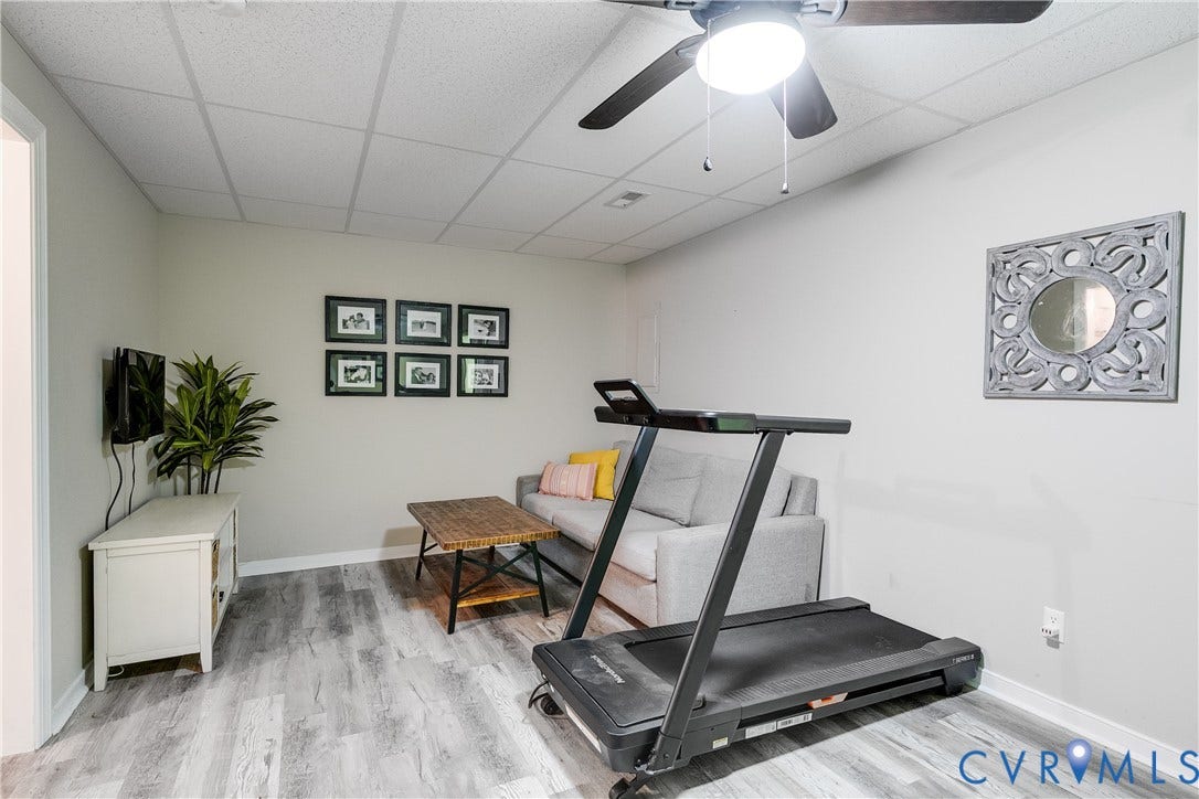 Versatile finished room featuring wood-finish LVP flooring, recessed lighting, a ceiling fan, and crisp white trim