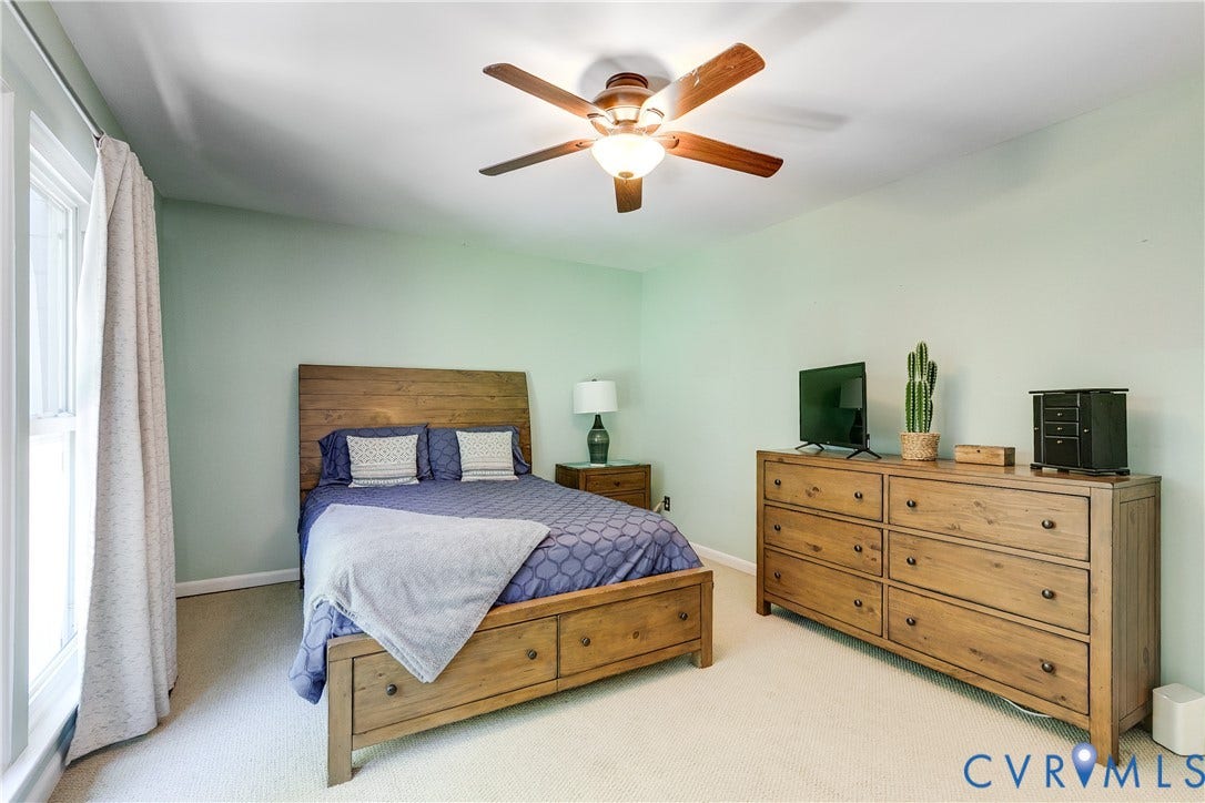 Bright bedroom featuring a ceiling fan with integrated lighting, light-toned wall paint, and soft carpet flooring