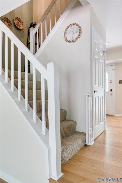 Carpeted staircase with white balusters and handrail