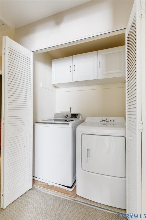 Dedicated laundry closet featuring louvered bi-fold doors, white upper cabinetry, and a washer and dryer