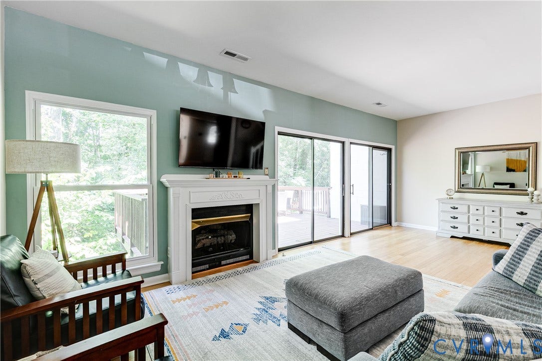 Living area featuring a fireplace with a white mantel, light wood-finish flooring, and light colored accent wall