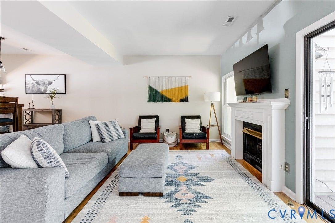 Living area featuring wood-finish flooring, a white fireplace surround, and glass sliding doors