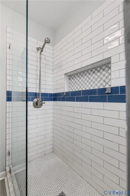 Shower enclosure featuring white subway tile, a bold blue accent tile band, and a mosaic-tiled niche
