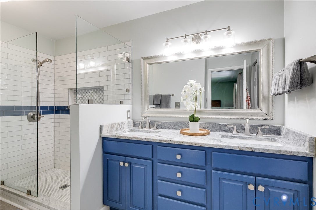 Walk-in shower with clear glass enclosure, subway tile surround, and mosaic tile accent