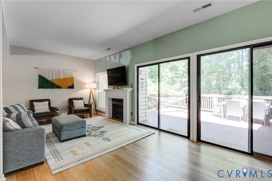 Living area featuring light wood-finish flooring, a white mantel fireplace, and a light colored accent wall