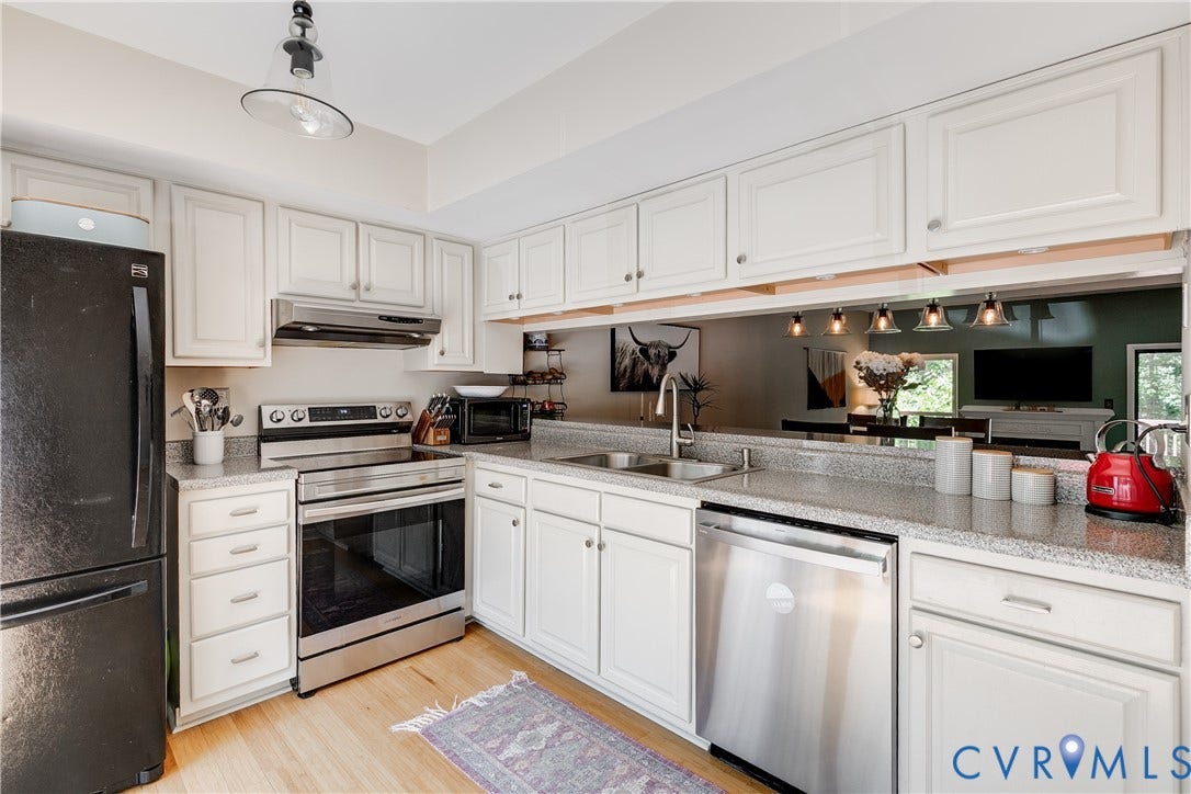 Kitchen featuring white cabinetry with silver hardware, granite-style countertops, stainless steel appliances including a range and dishwasher, and wood-finish flooring