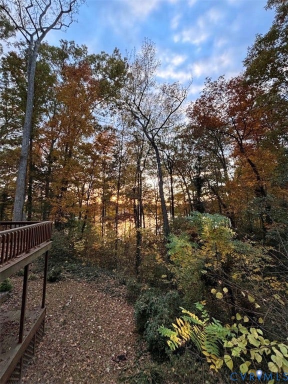 Wood deck overlooking a wooded landscape with a body of water in the background