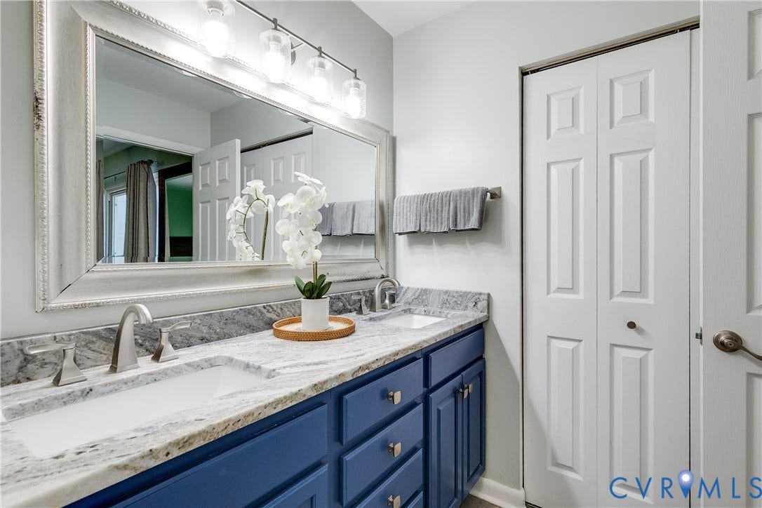 Double vanity with blue cabinetry, dual undermount sinks, and a light-toned stone countertop
