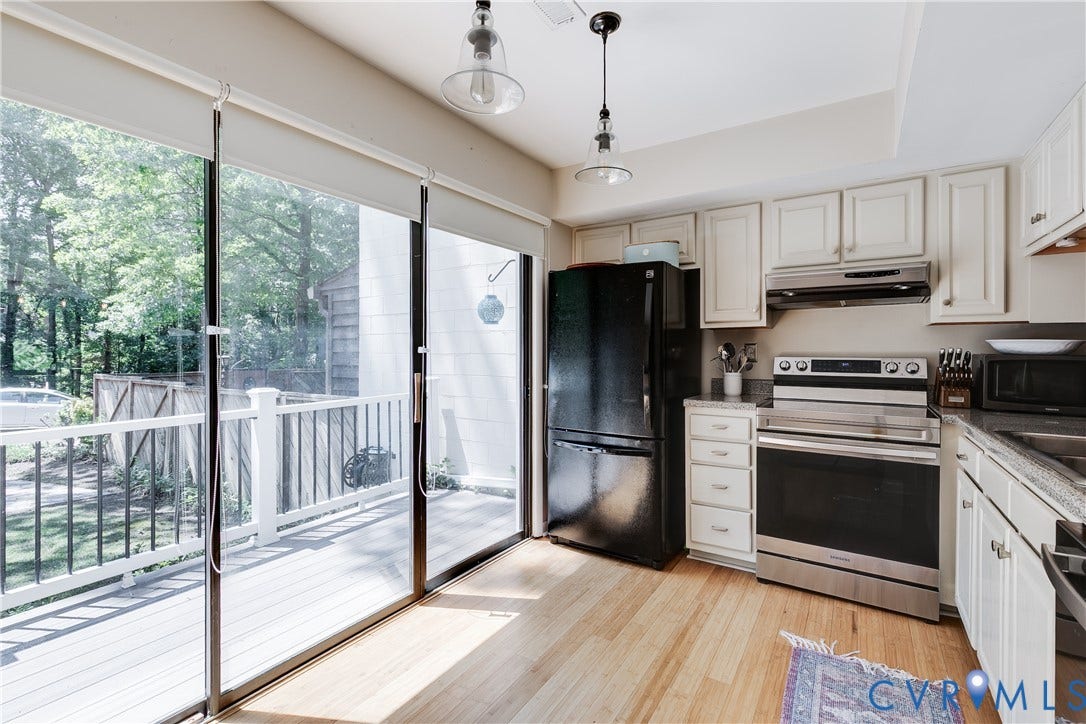 Kitchen featuring wood-finish flooring, white cabinetry, a stainless steel range with overhead hood, and granite countertops