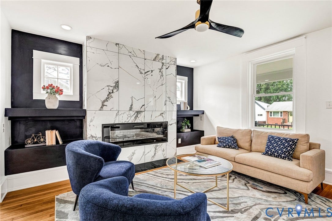 503 Pollock Street, Richmond, VA 23222 Integrated electric fireplace, large format marble-look tile surround, built-in shelving, wood-finish flooring, and a modern ceiling fan