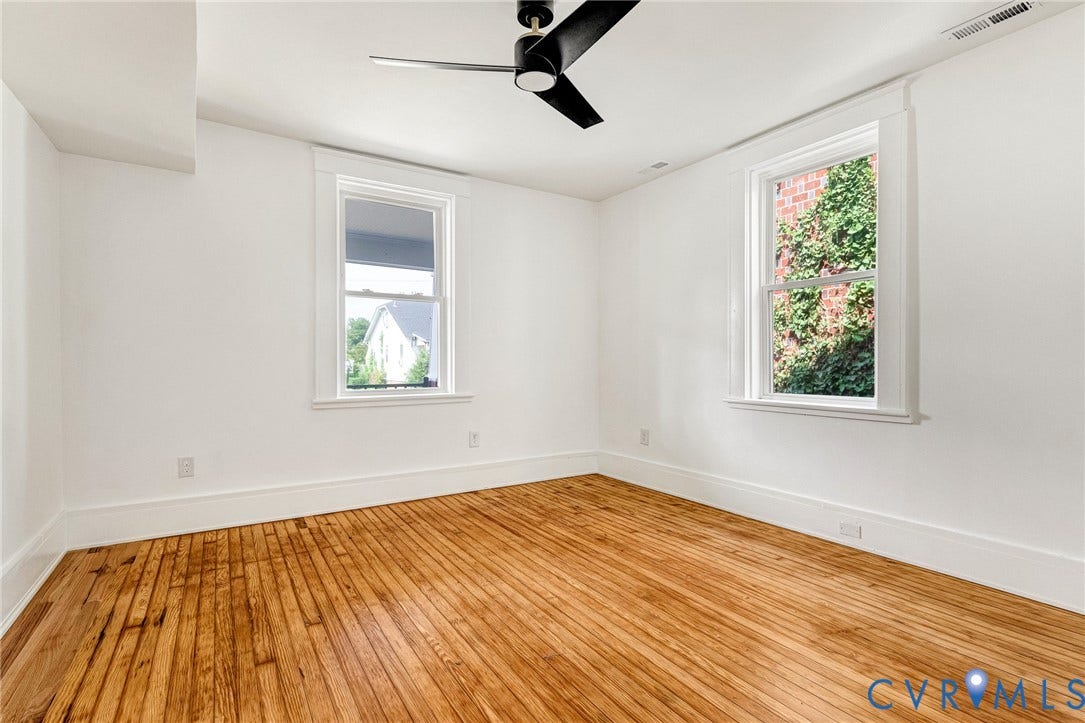 503 Pollock Street, Richmond, VA 23222 Hardwood flooring with a natural finish, white painted walls, two windows with white trim, and a black ceiling fan