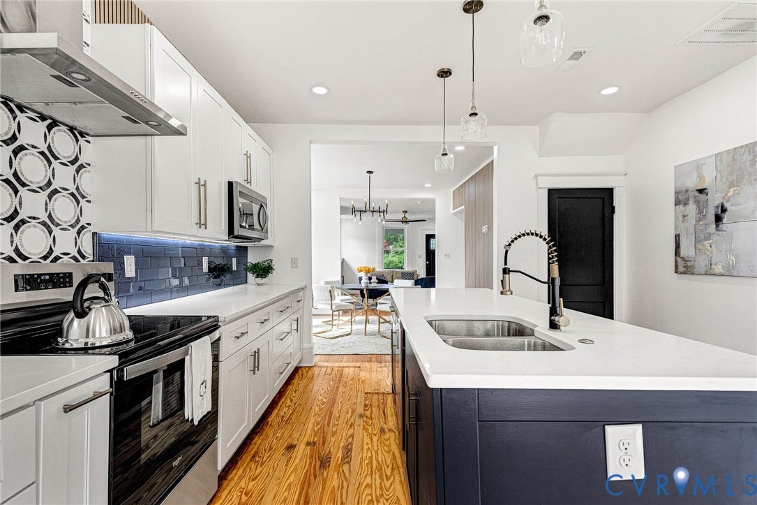 503 Pollock Street, Richmond, VA 23222 Kitchen featuring an island with double basin sink, white countertops, wood-finish flooring, and white cabinetry with stainless steel appliances