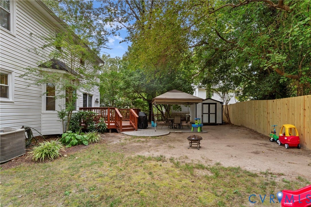 Expansive backyard featuring a wood deck, concrete patio, privacy fencing, and a storage shed