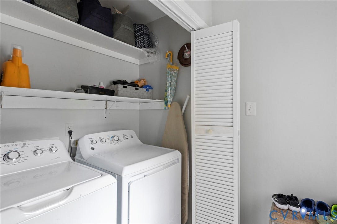 Laundry area with bi-fold louvered doors, two white appliances, and wall-mounted shelving