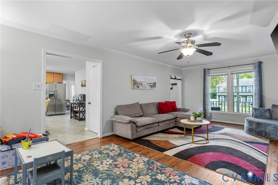 Hardwood flooring, ceiling fan with integrated lighting, crown molding, and a wide entryway to the kitchen