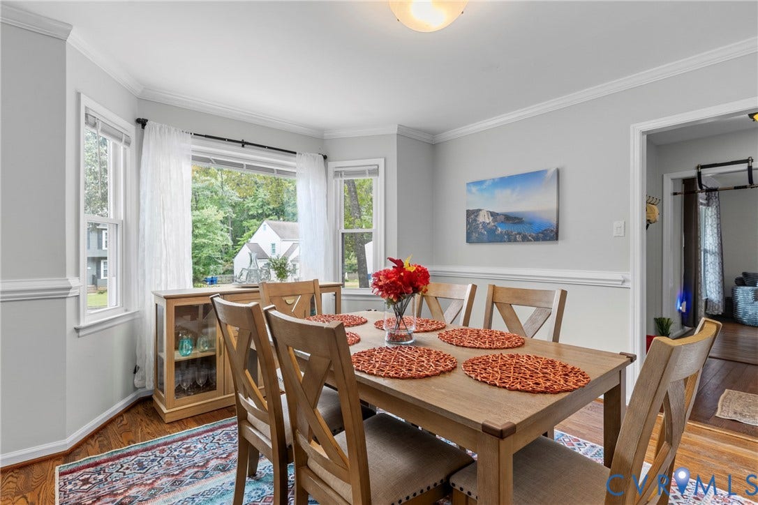 Bay window with multiple panes, crown molding, chair rail molding, wood-finish flooring, and a built-in light fixture