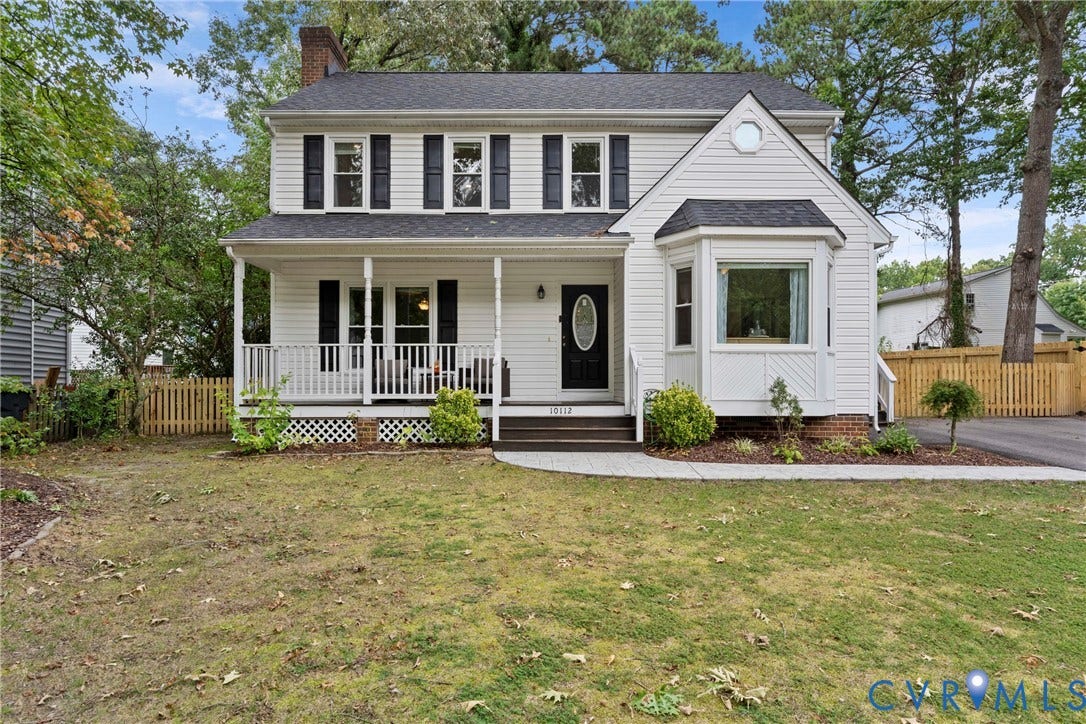 Traditional two-story exterior with white siding, covered front porch with white railing, and a bay window