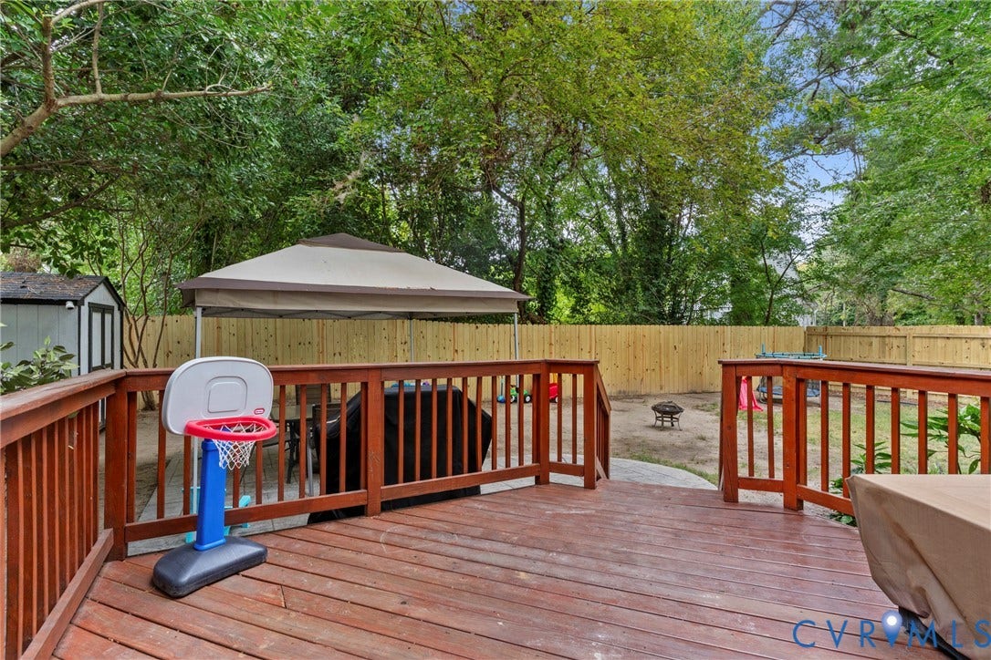 Expansive wood deck with railings, privacy fencing, and a separate structure in the yard