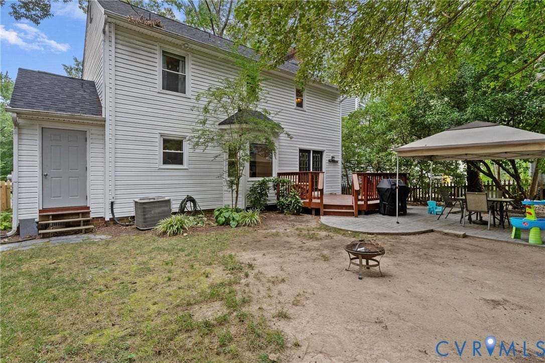 Two-story exterior with white siding, rear wood deck, and a paver patio