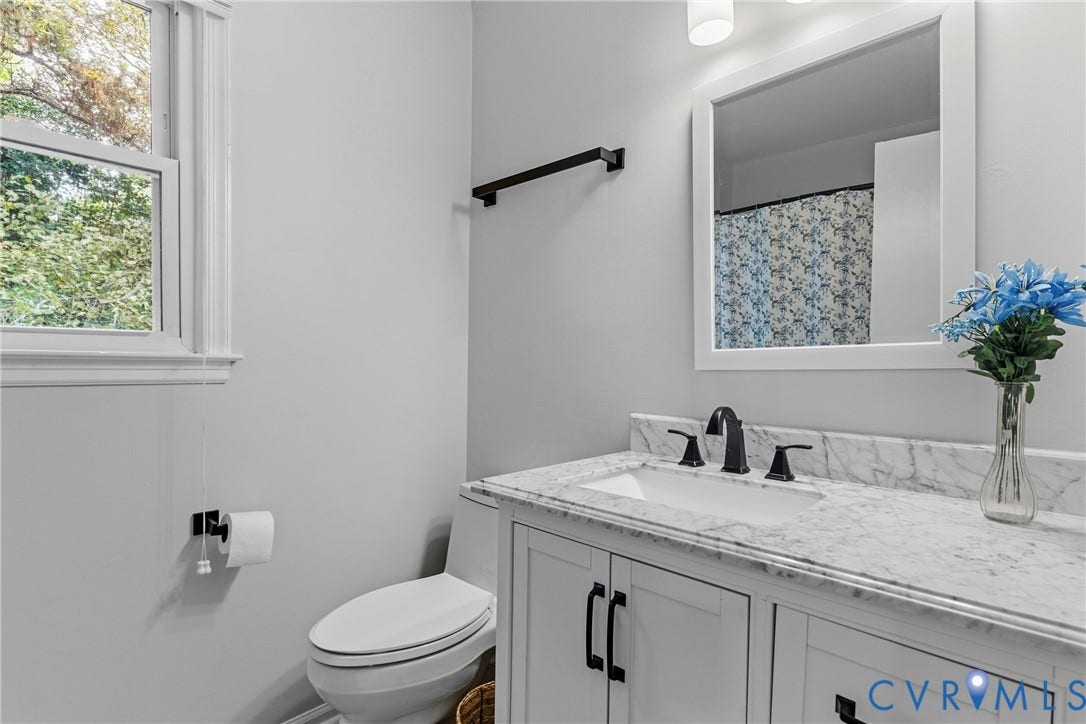 White vanity with a stone-finish countertop, integrated sink, and matte black hardware
