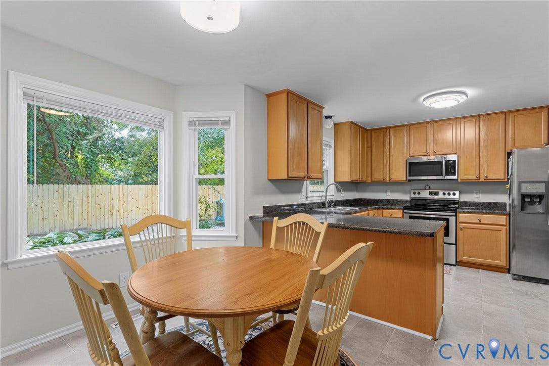 Kitchen featuring wood cabinetry, stainless steel appliances, dark countertops, and tiled flooring