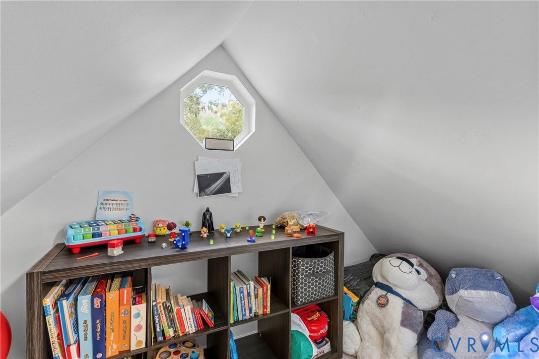 Attic space featuring an octagonal window, sloped ceilings, and white wall finishes