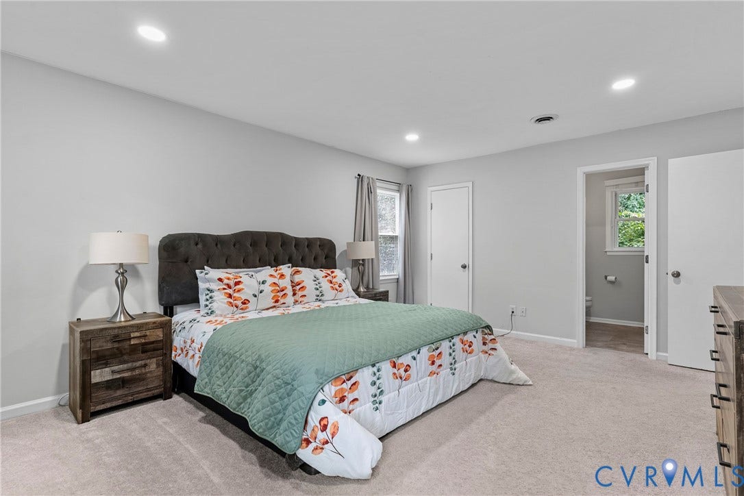 Recessed ceiling lighting, light-toned wall paint, carpeted flooring, and a window with curtain rods