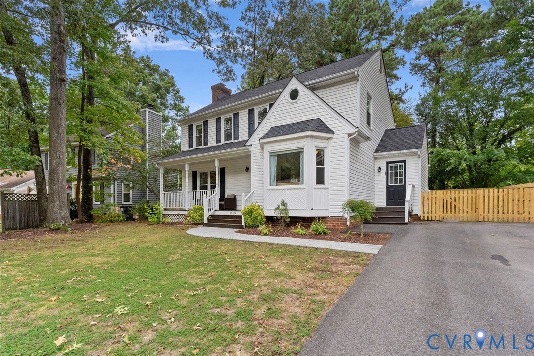 White siding exterior with black shutters, covered front porch, bay window, and gabled roofline