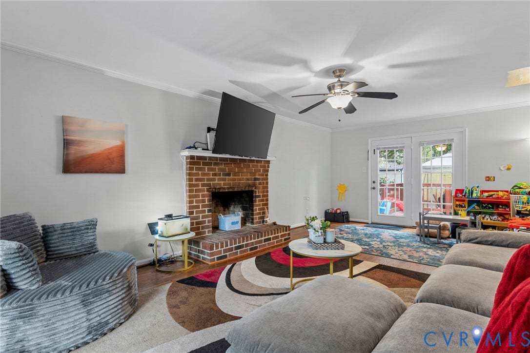 Brick fireplace with hearth, wood-finish flooring, ceiling fan with integrated lighting, and French doors leading to an exterior space