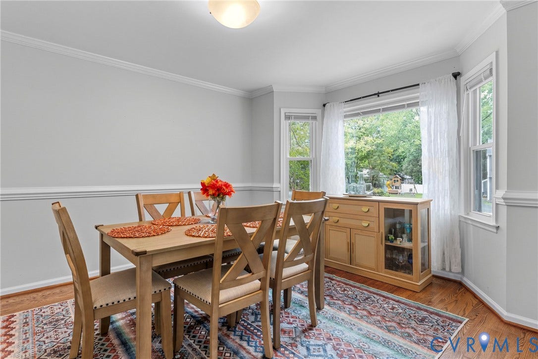 Bay window with multiple panes, crown molding, chair rail, and wood-finish flooring