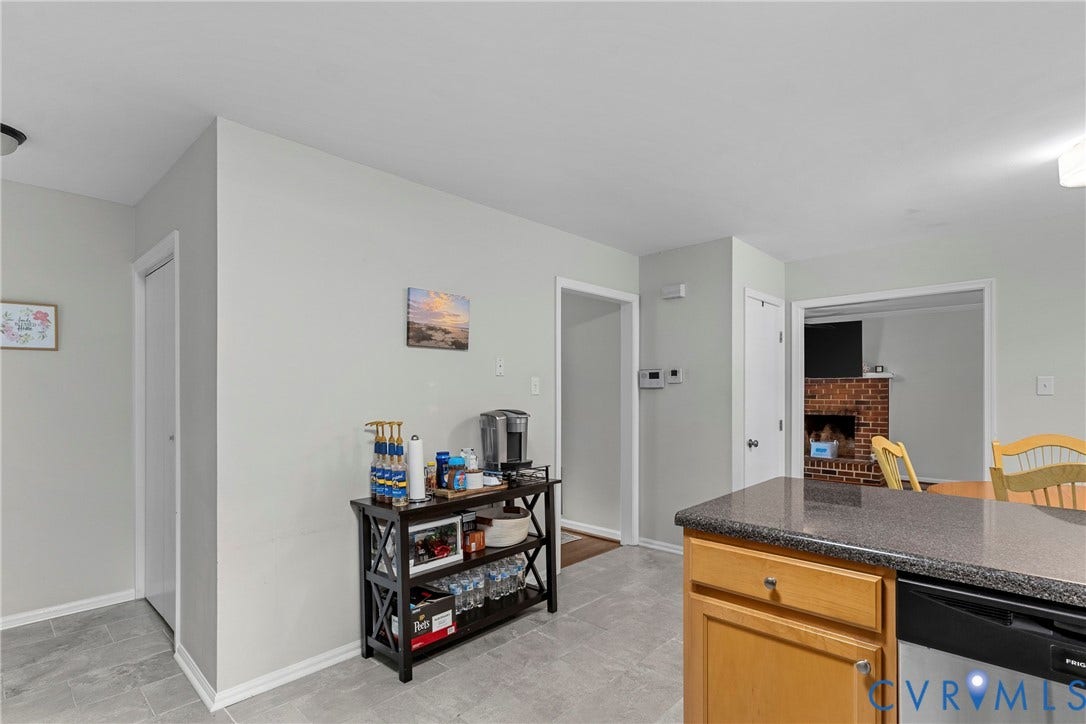 Kitchen area featuring wood-finish cabinetry, dark countertop, and integrated dishwasher
