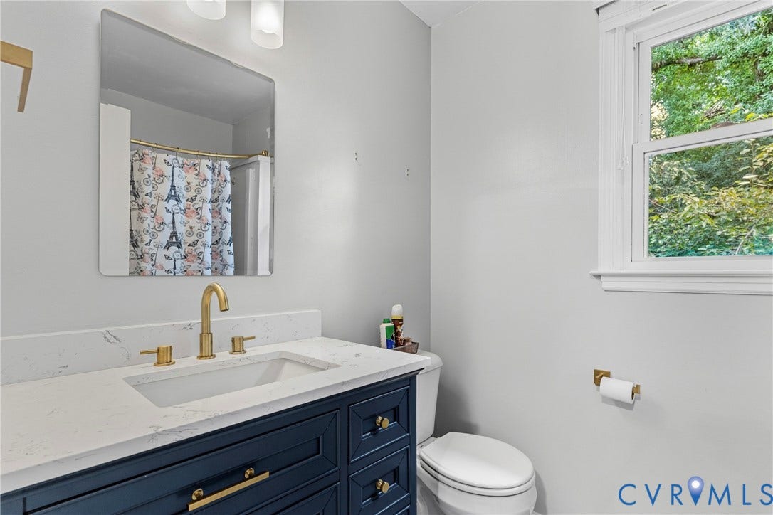 Navy blue vanity with gold-tone hardware, rectangular undermount sink, white countertop, and gold-tone faucet
