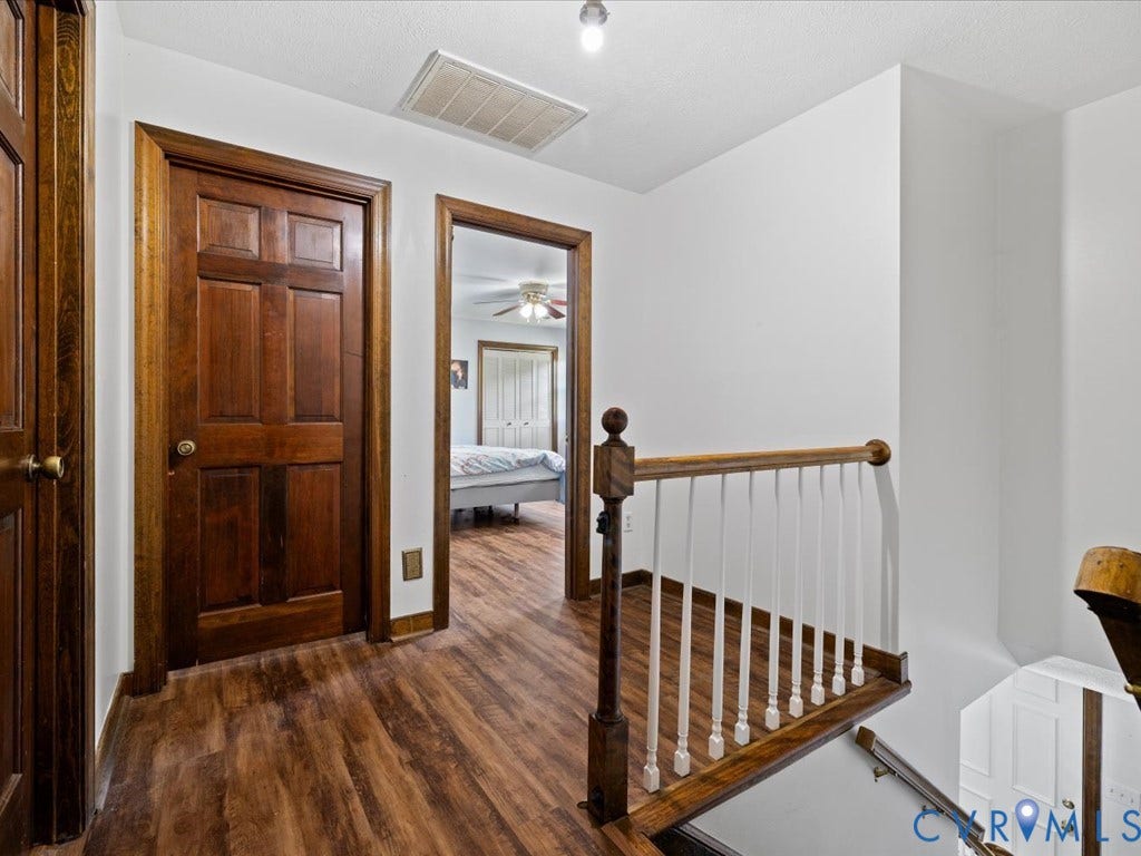 Wood-finish flooring throughout, bright white walls, and dark wood doors