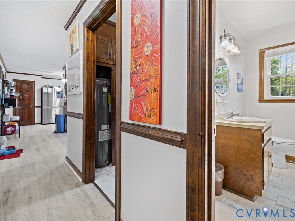 Wood-finish flooring throughout, with a bathroom featuring a vanity with an integrated sink and a window providing natural light