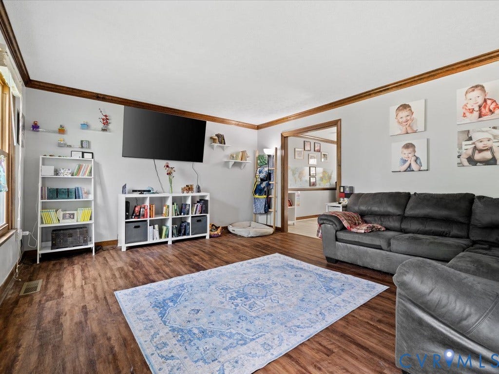 Spacious room with wood-finish flooring, white walls, and wood trim