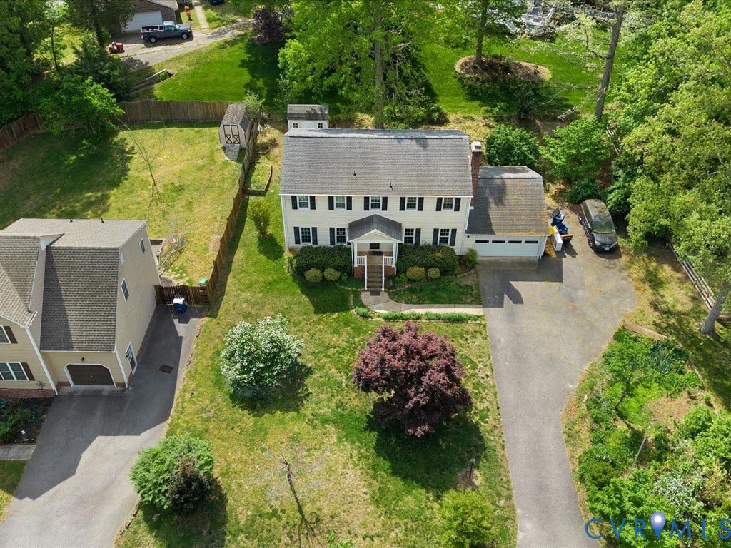 Two-story residence with a front entry portico, an attached garage, and a long asphalt driveway