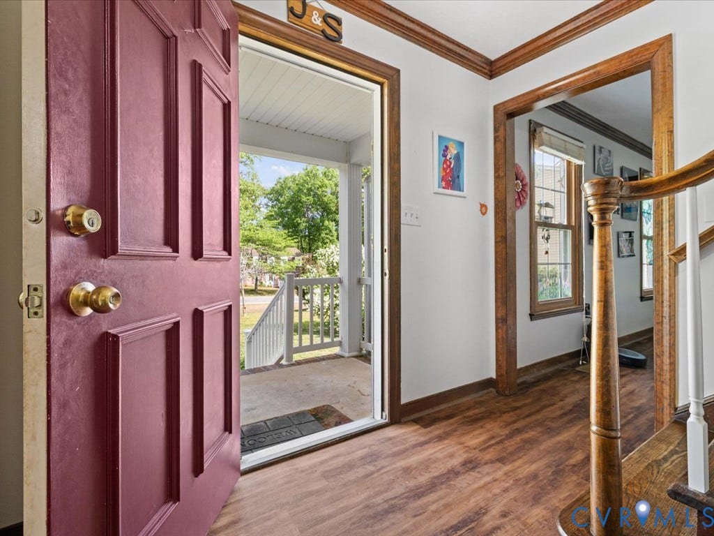 Wood-finish flooring throughout, solid panel entry door, and wood-toned trim details