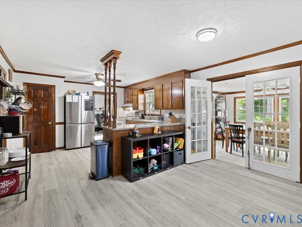 Wood-finish flooring throughout, wood cabinetry, built-in breakfast bar, and French doors